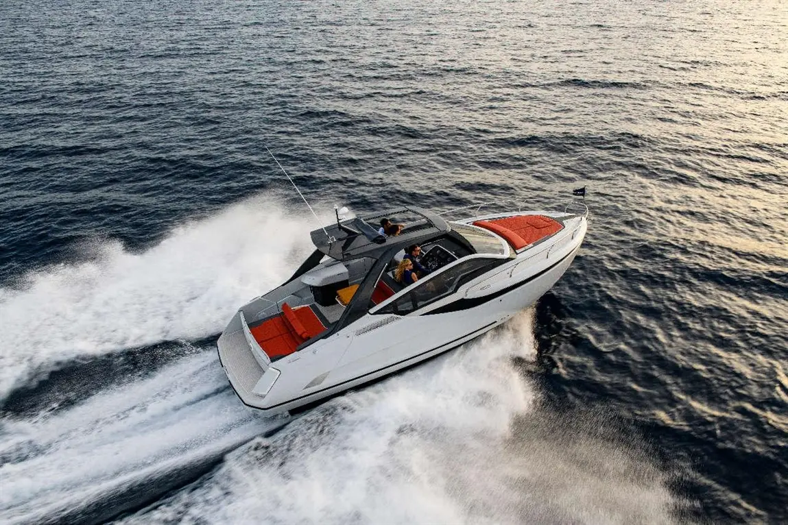A sleek motorboat speeds across open water, displaying colorful seating and two passengers at the controls.